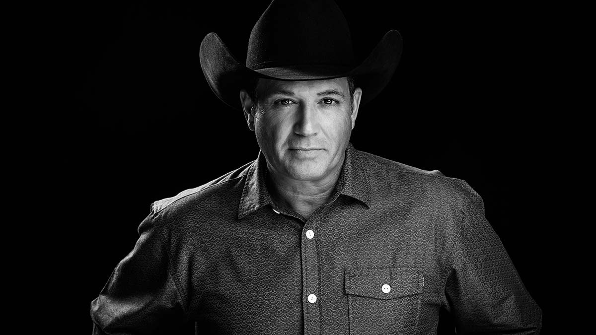 Man in cowboy hat at Tracy Byrd Rib Fest 2026, gazing neutrally at camera, black background.