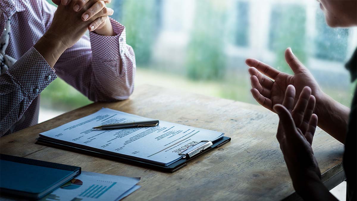 Two people discuss a resume at a table during the Open Hire Event Watertown.